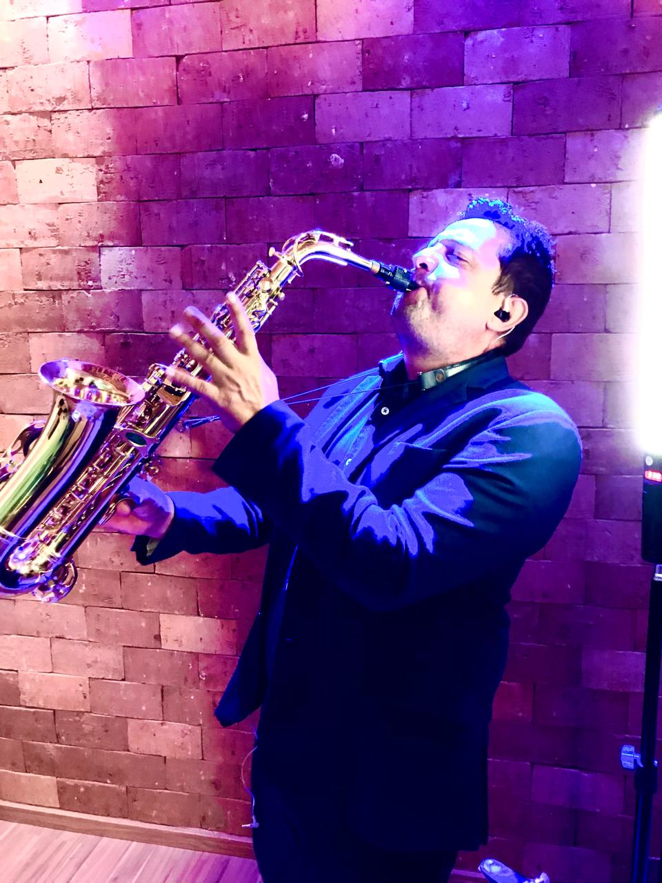 Felipe em close tocando saxofone sob luzes de palco